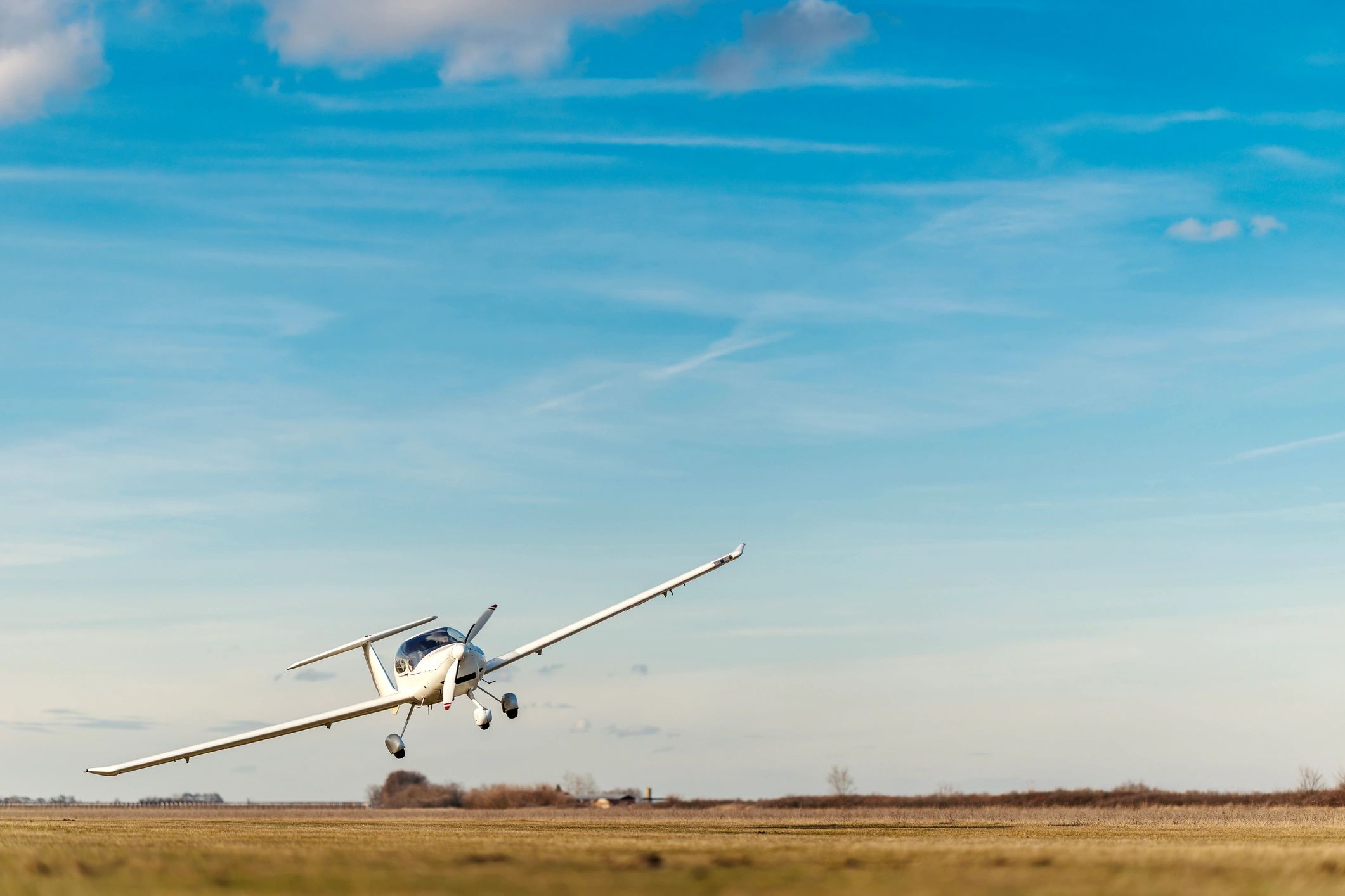 Small piston airplane taking off from a grass airfield